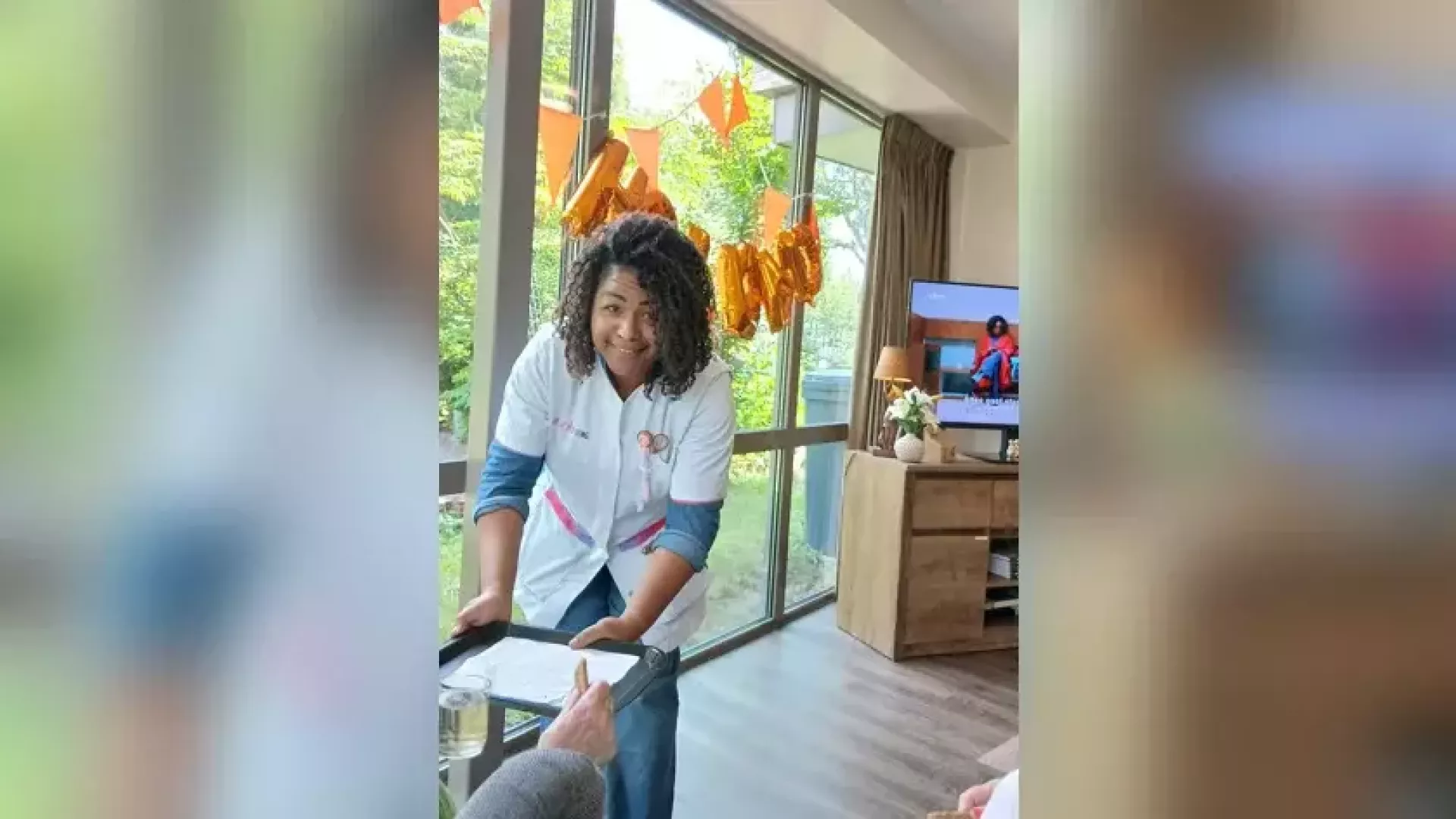 Een persoon bedient gasten in een woonkamer met feestdecoraties.
